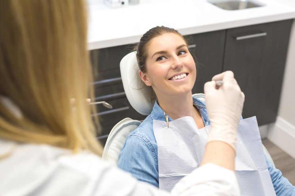 A dental hygienist talking with a smiling patient in the chair