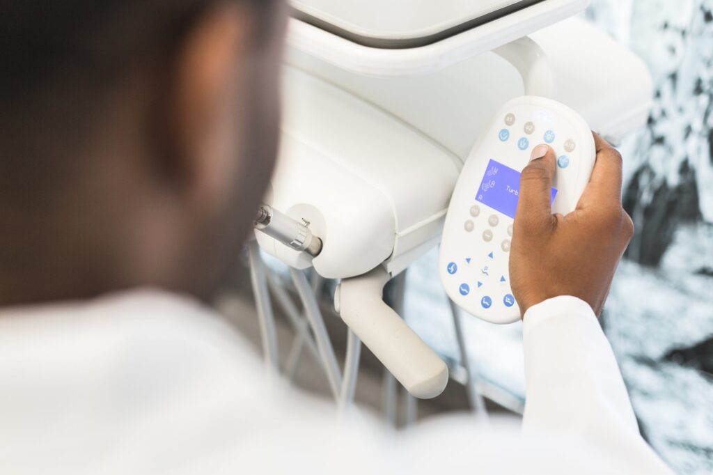 A hand pressing a button on a dental chair control panel