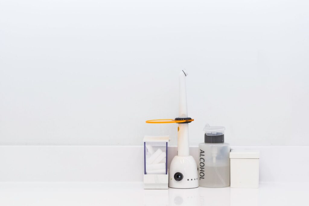 A dental curing light and an electric toothbrush beside a small bottle