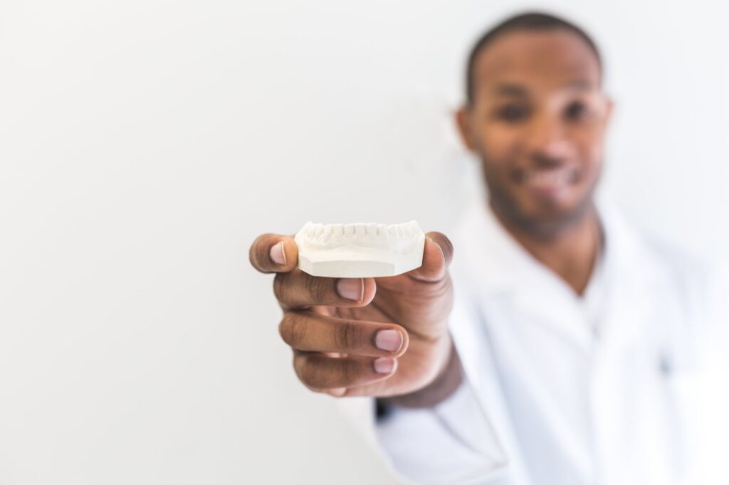 A dentist holding a clear dental aligner