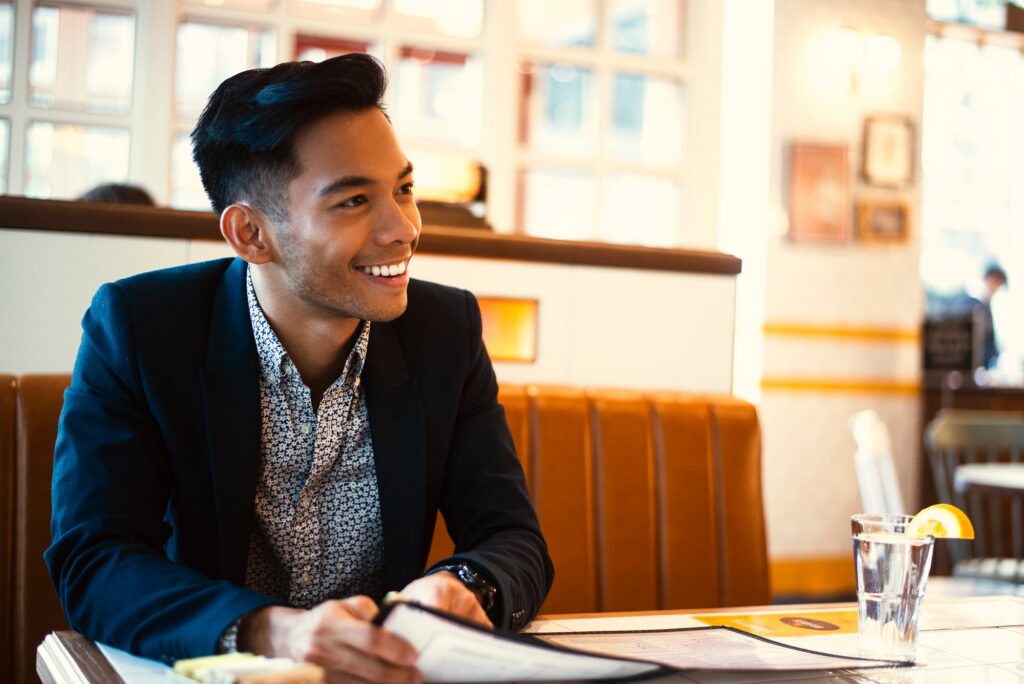 A smiling man in a blazer seated at a table