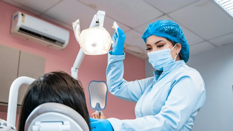 A dentist examining a patient's teeth in the chair