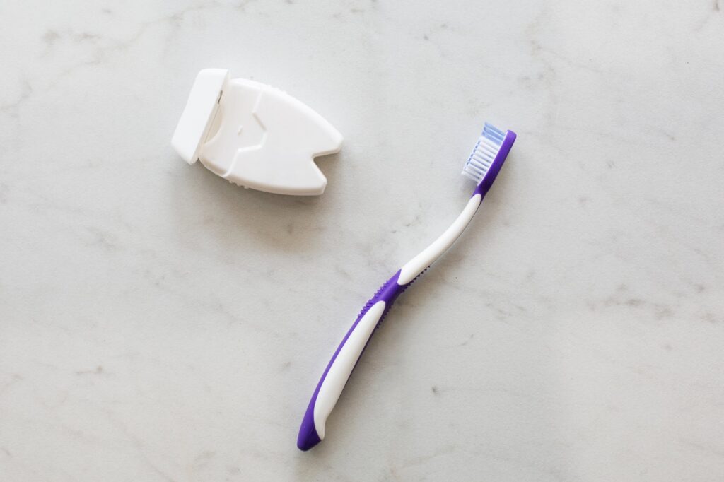 A toothbrush and a floss pick on a marble surface